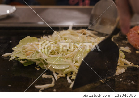 The process of cooking monjayaki ingredients on a griddle; the preparation of cabbage. The process of cooking monjayaki ingredients on a griddle; the preparation of cabbage. 138340399