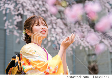 身穿和服的20歲女子,背景是盛開的櫻花。 身穿和服的20歲女子,背景是盛開的櫻花。 138341467