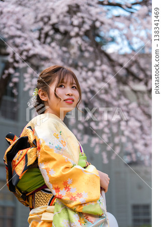 身穿和服的20歲女子,背景是盛開的櫻花。 身穿和服的20歲女子,背景是盛開的櫻花。 138341469
