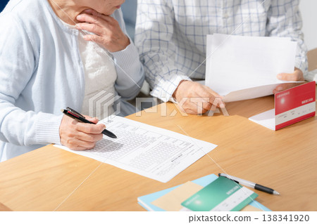 一對老年夫婦正在填寫臨終關懷計劃的相關文件。 一對老年夫婦正在填寫臨終關懷計劃的相關文件。 138341920