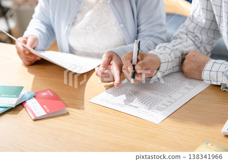 Senior couple filling out paperwork for end-of-life planning. 138341966