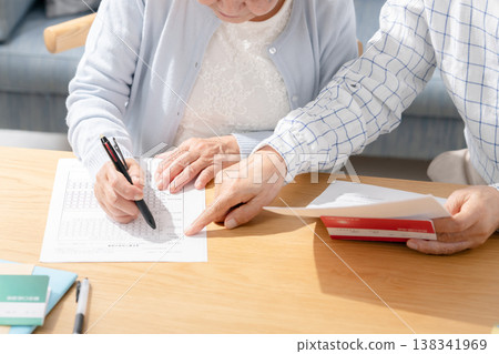 Senior couple filling out paperwork for end-of-life planning. Senior couple filling out paperwork for end-of-life planning. 138341969