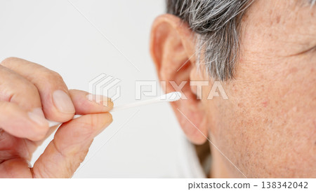 一位老人在用棉花棒清潔耳朵 138342042