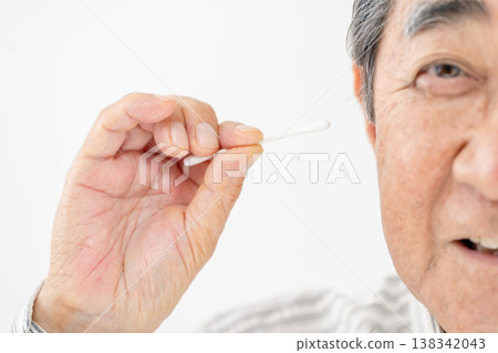 一位老人在用棉花棒清潔耳朵 138342043