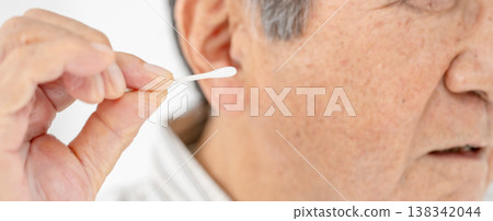 Senior man cleaning his ears with a cotton swab Senior man cleaning his ears with a cotton swab 138342044