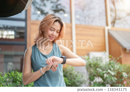Asian woman in sportswear checking time looking at a watch preparing to go exercise at gym fitness. Asian woman in sportswear checking time looking at a watch preparing to go exercise at gym fitness. 138343175