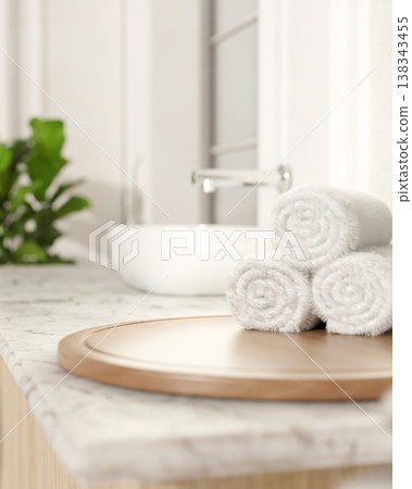 White towels on round wooden tray at marble sink counter aside houseplant in bright modern bathroom 138343455