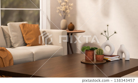 Cactus and pot plant on tray with books and creative vases on wooden table aside sofa in living room Cactus and pot plant on tray with books and creative vases on wooden table aside sofa in living room 138343457