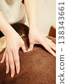 治療師隔著一條棕色毛巾，用拇指用力按壓肩膀。 138343661