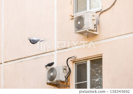 air conditioner is installed on facade of the building. air conditioner compressor is on wall. air conditioner is installed on facade of the building. air conditioner compressor is on wall. 138343692