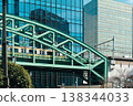 A railway bridge spanning a cluster of city buildings and a commuter train. 138344033
