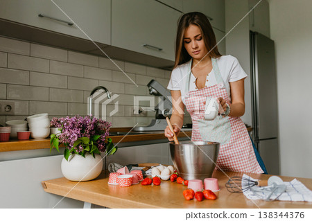 Young woman decorating cupcakes in bright kitchen 138344376
