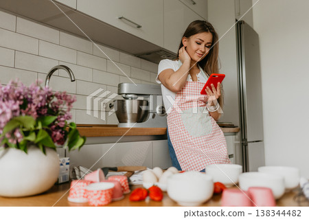 Young woman planning to cook, looking for recipe on internet on her smartphone at home kitchen 138344482