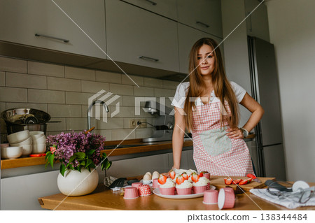 The action of making red velvet cupcakes. Woman hand adding sugar sprinkle on cupcake. 138344484