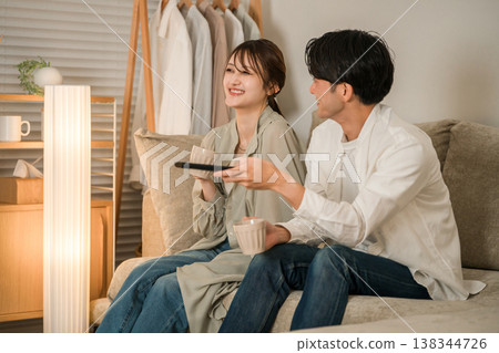 A couple sitting on the sofa in the living room watching TV at night A couple sitting on the sofa in the living room watching TV at night 138344726