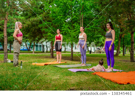 Women in colorful sportswear standing in a line waiting for yoga class to start on mats in park. Waiting, yoga, line, mats, park, sportswear. 138345461