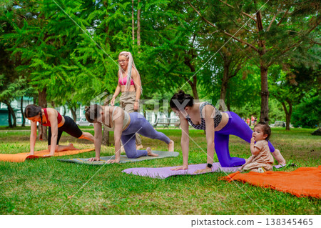 Yoga instructor leading group women practicing lunge pose on mats with children nearby in city park. Lunge pose, yoga, instructor, mats, group, city park, children. Yoga instructor leading group women practicing lunge pose on mats with children nearby in city park. Lunge pose, yoga, instructor, mats, group, city park, children. 138345465