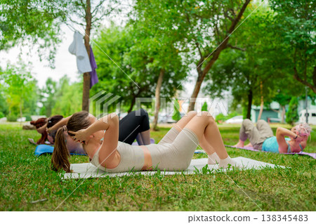 Group of women doing abs exercises on grass mats outdoors together during summer fitness class. Abs exercises, mats, group, fitness, outdoors, women. Group of women doing abs exercises on grass mats outdoors together during summer fitness class. Abs exercises, mats, group, fitness, outdoors, women. 138345483