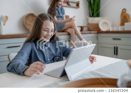Girl with denim dress doing homework and writing in notebook at cozy kitchen table. Homework, notebook, kitchen, denim, girl. Girl with denim dress doing homework and writing in notebook at cozy kitchen table. Homework, notebook, kitchen, denim, girl. 138345504