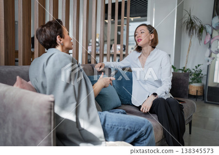 Young woman presenting while using phone in office, standing beside potted plant and table. Presentation, phone, office, standing, teamwork, business. Young woman presenting while using phone in office, standing beside potted plant and table. Presentation, phone, office, standing, teamwork, business. 138345573