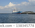 Image of shipping and logistics: A port with a large blue ship and a breakwater. 138345778
