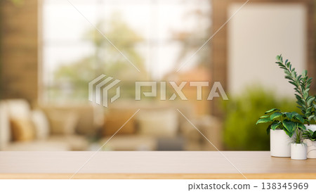 Potted plants on wooden counter table across sofa and glass window in a blurred living room or cafe. Potted plants on wooden counter table across sofa and glass window in a blurred living room or cafe. 138345969