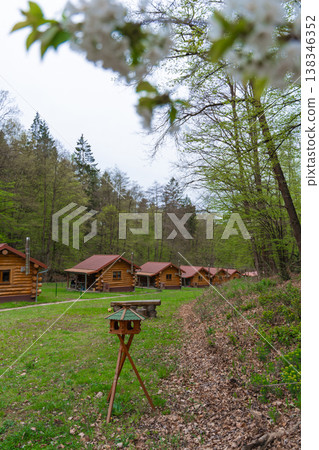 Row of wooden cabins in spring forest with bird feeder and picnic area in rural Czech countryside Row of wooden cabins in spring forest with bird feeder and picnic area in rural Czech countryside 138346352