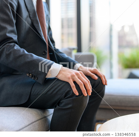 A man in a suit is waiting in the lobby. 138346558