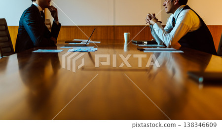 Two businessmen facing each other in a conference room. Two businessmen facing each other in a conference room. 138346609