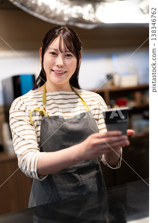 一位微笑的咖啡館員工隔著櫃檯遞給你一杯外帶咖啡。 一位微笑的咖啡館員工隔著櫃檯遞給你一杯外帶咖啡。 138346762