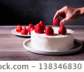 The finishing touches on a strawberry shortcake: The process of decorating by topping it with strawberries. 138346830