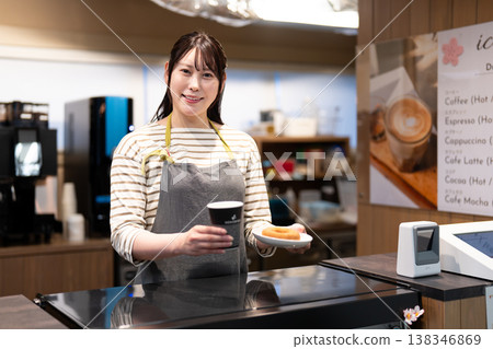 A smiling cafe employee serving coffee and donuts 138346869