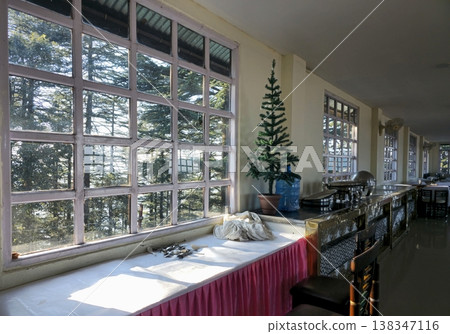 Sunlit dining area with large glass windows, buffet counter, and forest view outside, capturing a quiet mountain hotel interior with natural light. 138347116