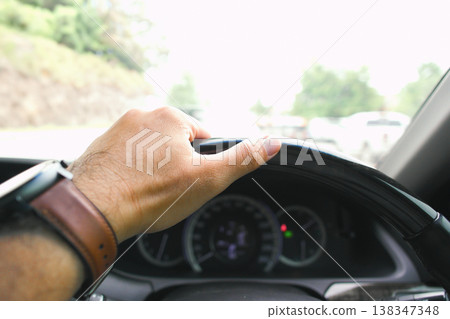 Closeup of driver hand on car steering wheel driving on the road Closeup of driver hand on car steering wheel driving on the road 138347348