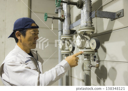 一名商人在工廠設施進行設備維護 一名商人在工廠設施進行設備維護 138348121