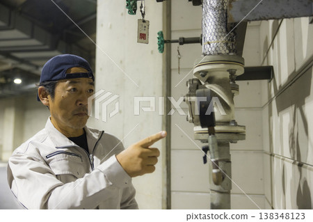 A businessman performing equipment maintenance at a factory facility A businessman performing equipment maintenance at a factory facility 138348123