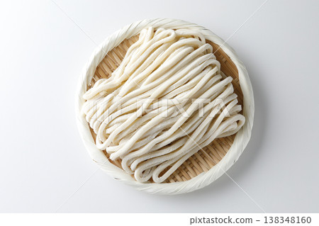 Raw udon noodles served in a bamboo basket against a white background. Raw udon noodles served in a bamboo basket against a white background. 138348160