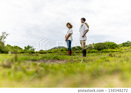 一位年輕的農民站在鄉村風景中。 138348272