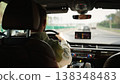 Rear view of a man driving a modern car on the highway, focusing on road safety. Navigation technology, travel insurance during a road trip, and car insurance. 138348483