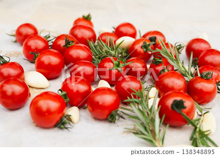 Fresh cherry tomatoes with garlic cloves and rosemary on a light surface. Fresh cherry tomatoes with garlic cloves and rosemary on a light surface. 138348895