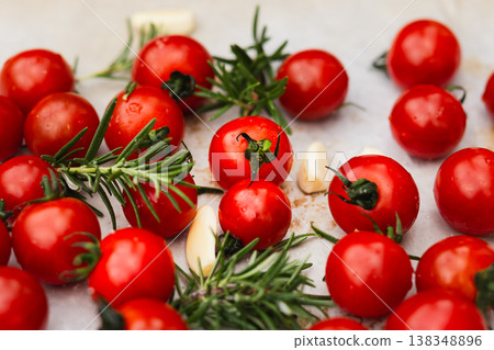 Fresh cherry tomatoes with garlic cloves and rosemary on a light surface. Fresh cherry tomatoes with garlic cloves and rosemary on a light surface. 138348896