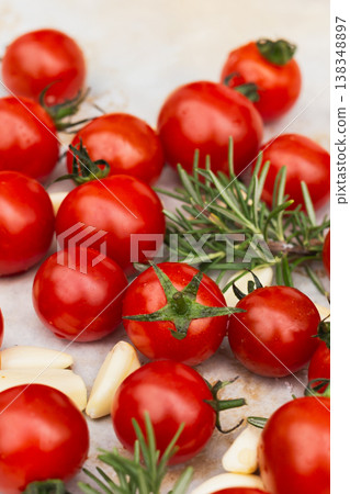 Fresh cherry tomatoes with garlic cloves and rosemary on a light surface. 138348897