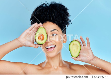 Happy woman, face and avocado for natural skincare, beauty or diet against a blue studio background. Female person or model smile with organic vegetable for nutrition, vitamin C or skin wellness 138349788