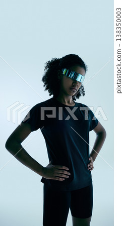 Teen girl wearing reflective futuristic visor standing confident in studio with minimal background. 138350003
