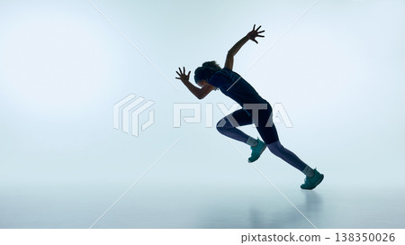 Teenager performing dynamic running jump in studio with clean minimal background. Teenager performing dynamic running jump in studio with clean minimal background. 138350026
