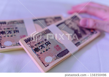 一隻手在紫色的光芒中觸摸著一疊鈔票。 138350496