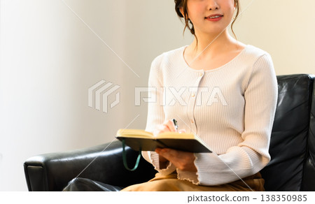 一位女士在筆記本上寫著什麼。 138350985