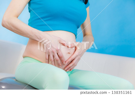 Pregnant woman making heart shape on belly with hands Pregnant woman making heart shape on belly with hands 138351161