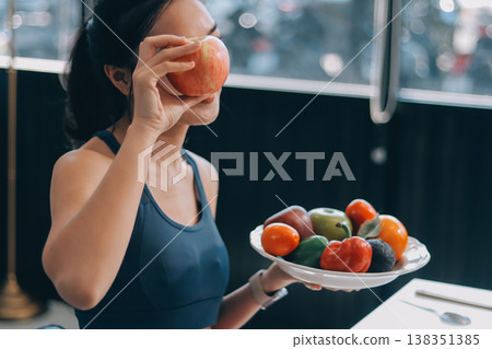 Fit young Asian women in activewear sitting on yoga mat and eating fresh vegetable salad after workout, representing clean eating, fitness lifestyle, wellness routine and health balance. Fit young Asian women in activewear sitting on yoga mat and eating fresh vegetable salad after workout, representing clean eating, fitness lifestyle, wellness routine and health balance. 138351385