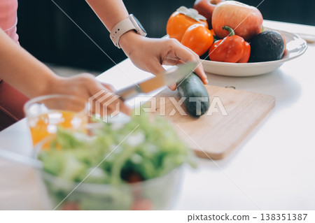Fit young Asian women in activewear sitting on yoga mat and eating fresh vegetable salad after workout, representing clean eating, fitness lifestyle, wellness routine and health balance. 138351387